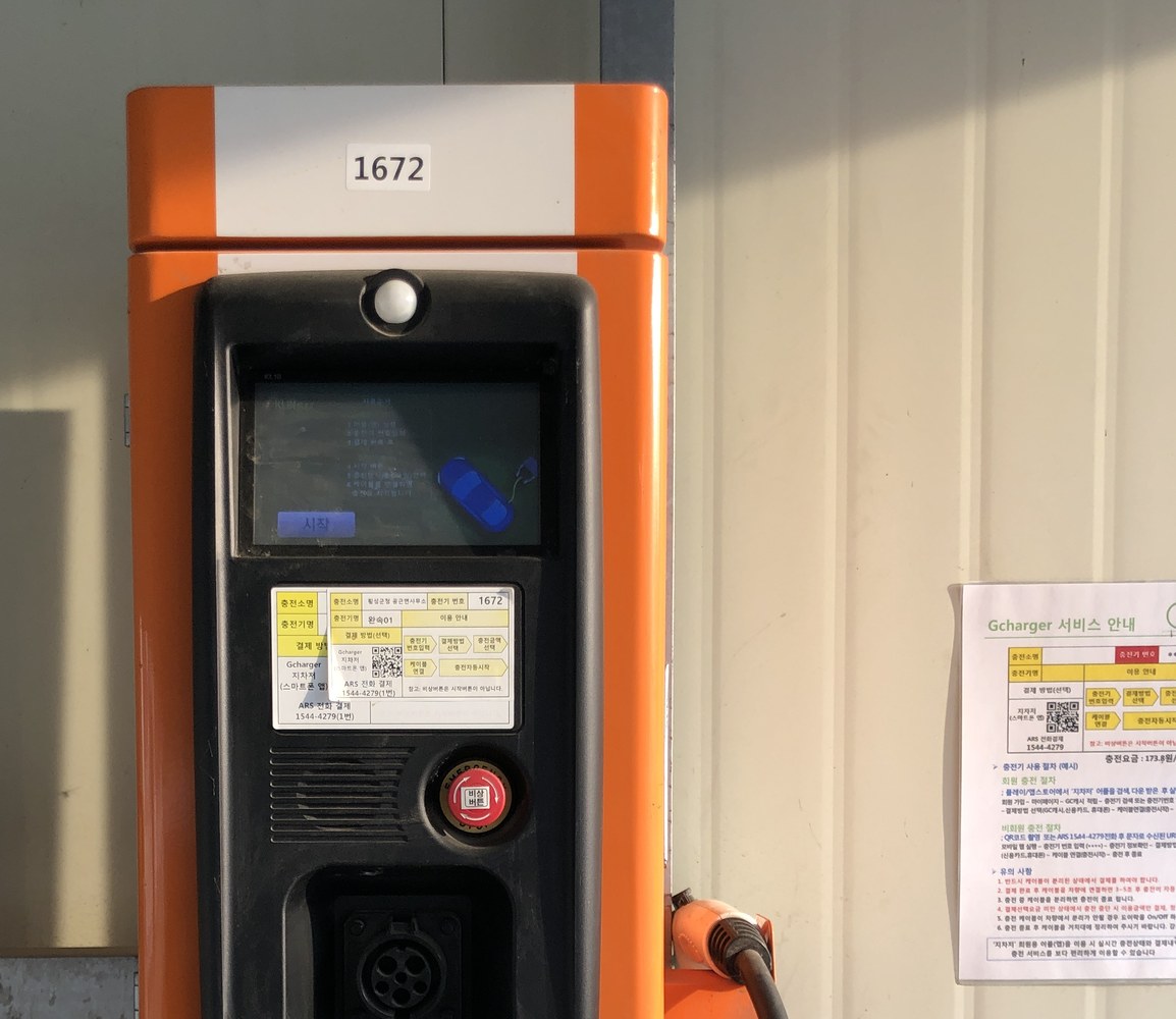 상단 기기 번호와 화면 아래 운영 안내 스티커가 있는 Gcharger 충전기